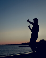 Person pointing beautiful coastline and sunset. Silhouette portrait.