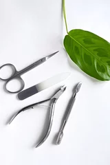 Poster A set of cosmetic tools for manicure and pedicure on a light background. Nail file, nail scissors, pusher and pliers top view. © lara