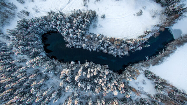 Aerial perspective (straight above) of a small fount in forests at winter. Kiikunlahde, Finland.