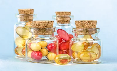 Gordijnen Glazen apotheekflessen met rode en gele pillen op blauwe achtergrond. © Albert Ziganshin