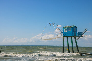 Fototapeta premium cabane de pêcheur bleue avec un filet à carrelet pour pêcher à marée haute sur la plage de Saint-michel-chef-chef