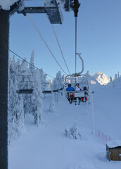 Family in ski lift. Morning sun in ski and outdoor center. Ruka ski resort, Finland.