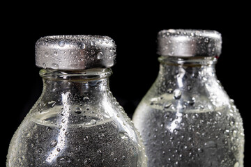 Glass bottles with fresh drinking water. Water drops on glass containers for water storage.
