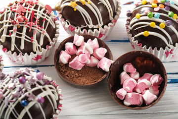 Black chocolate shells filled with cocoa powder and marshmallows on the table . Cocoa bomb melt when hot milk is added, open in a mug and create a trendy delicious drink. Closeup view, selective focus