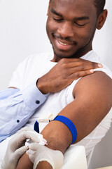 Doctor Injecting Patient With Syringe To Collect Blood