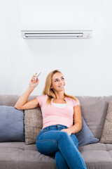 Woman Operating Air Conditioner With Remote Control