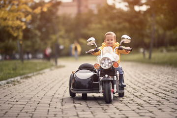 caucasian toddler driving replica of motorcycle outdoor