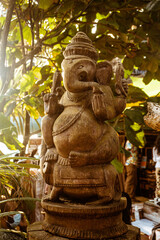 Posąg statua hinduskiego Boga Ganesha, na jasnym roślinnym tle. © insomniafoto