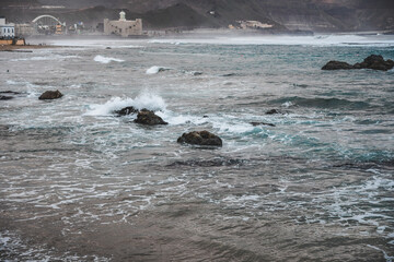 Fototapeta premium Big powerful waves at the beach hit breakwater. Winter season, windy and stormy weather. 