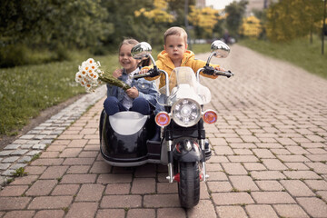 cute toddler driving little girl in sidecar of motorcycle toy on battery in colorful autumn park - obrazy, fototapety, plakaty