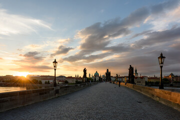 Fototapeta na wymiar Charles Bridge in the morning at dawn, Old Town of Prague. The sun rises over the Vltava river. Travel in the Czech Republic. Famous tourist places in Europe.