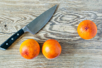 Blood Sicilian oranges on wooden cutting board with knife. ripe juicy citrus fruits on rustic...