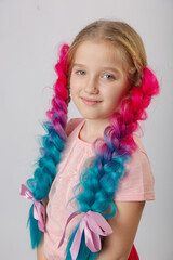 Cute little girl with blond hair and multi-colored bright canecalons with balloons on a light background