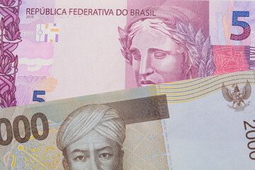 A macro image of a pink and purple five real bank note from Brazil paired up with a grey two thousand Indonesian rupiah bank note.  Shot close up in macro.