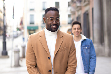 Cheeky man looking with a half smile and his friend laughing behind.