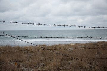 sea view through a barbed wire fence