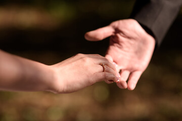 Man holds a woman's hand with a wedding ring or engagement ring on his finger. Close-up of hands.
