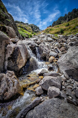 meltwater river flows through a rocky gorge from the top of a mountain, in the natural park of Aiguestortes, in the Catalan Pyrenees of Lerida, Spain