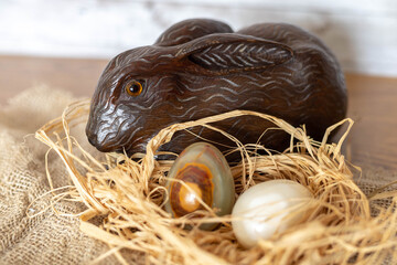Easter eggs made of decorative marble stone on a straw nest and a lucky bunny made of handcrafted wood for the amusement of children.