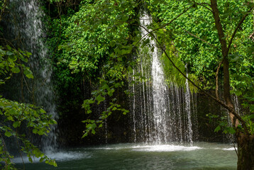 A waterfall amongst the lush green foliage portrays a feeling of peace and serenity. Bokeh effect.