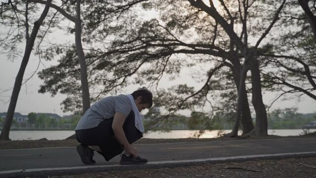 senior sport woman sit and tightening knot shoe lace. elderly  asian Runner Tying Shoelaces Before Jogging Workout at green lake park in evening sunset.