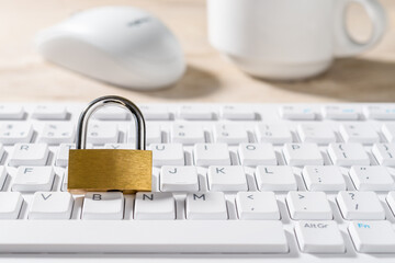Metal padlock on a white computer keyboard. Closed lock on a desktop keypad. Computer and internet security, save confidential data concepts. High key image. Copy space.
