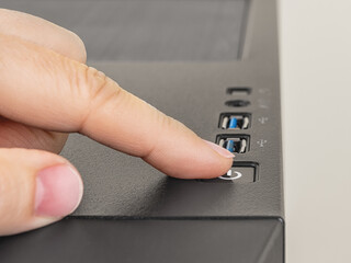 Finger is ready to press down the On Off button on the personal computer system unit. Power button on the top of desktop PC tower case. Hardware equipment concept.