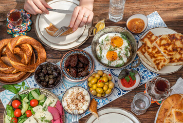 Delicious rich Traditional Turkish breakfast include tomatoes, cucumbers, cheese, butter, eggs, honey, bread, bagels, olives and tea cups. Ramadan Suhoor aka Sahur (morning meal before fasting). 
