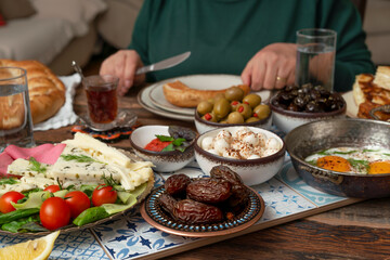 Delicious rich Traditional Turkish breakfast include tomatoes, cucumbers, cheese, butter, eggs, honey, bread, bagels, olives and tea cups. Ramadan Suhoor aka Sahur (morning meal before fasting). 