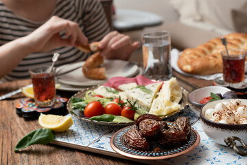 Delicious rich Traditional Turkish breakfast include tomatoes, cucumbers, cheese, butter, eggs, honey, bread, bagels, olives and tea cups. Ramadan Suhoor aka Sahur (morning meal before fasting). 