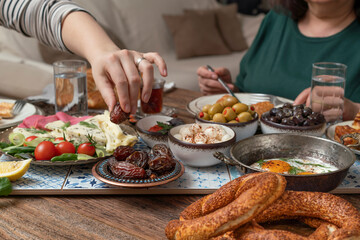 Delicious rich Traditional Turkish breakfast include tomatoes, cucumbers, cheese, butter, eggs, honey, bread, bagels, olives and tea cups. Ramadan Suhoor aka Sahur (morning meal before fasting). 