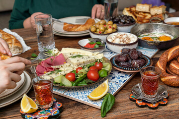 Delicious rich Traditional Turkish breakfast include tomatoes, cucumbers, cheese, butter, eggs, honey, bread, bagels, olives and tea cups. Ramadan Suhoor aka Sahur (morning meal before fasting). 
