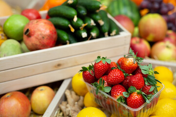Tray of strawberries on the counter of a vegetable store among vegetables and fruits.