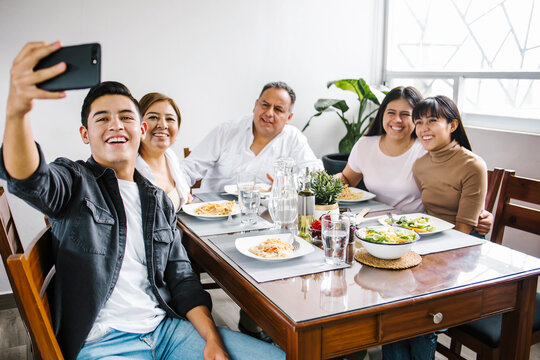 Latin Family Taking A Photo Selfie As They Enjoy Meal At Home Together In Latin America