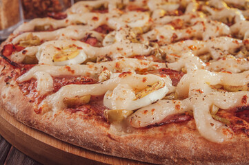 Pizza with mozzarella, calabrese sausage, eggs, catupiry, olive and oregano (Pizza especial de calabresa) - Closeup.