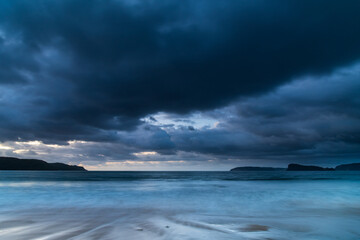 Drizzly sunrise seascape with seaweed on the beach