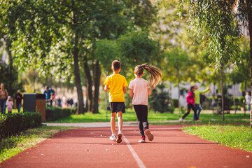 Kids run. Healthy sport. Child sport, heterosexual twins running on track, fitness. Joint training. Running training outdoor brother and sister pre-teen. Jogging with friend. Children athletes