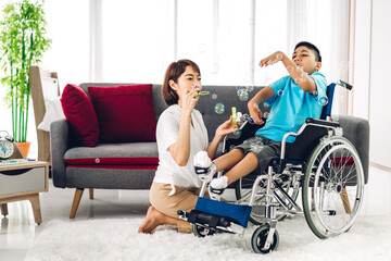 Portrait of asian physiotherapist carer helping and playing with special disabled child health problem by doing exercises sitting in wheelchair in rehabilitation clinic.disability care concept