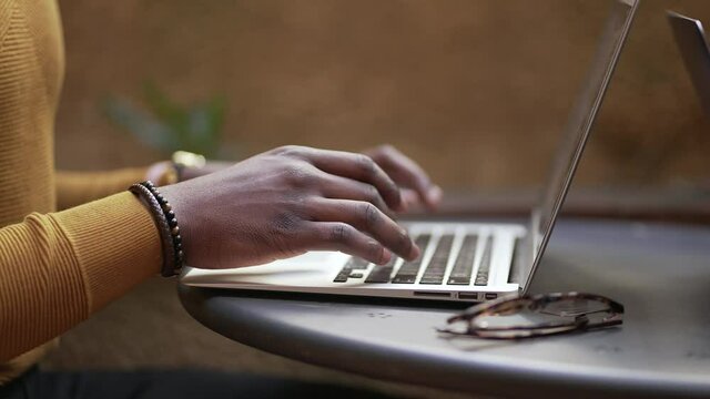 Close-up black african man hands typing on laptop computer