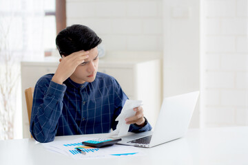 Fototapeta na wymiar Young asian man calculating expenses household about finance and frustrated on desk at home, male checking bill having stress and worried, debt and tax, expression and emotion, business concept.