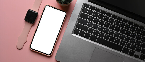 Horizontal image of female workplace with smart watch on pink pastel background.