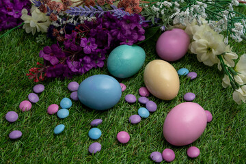 Pastel colored Easter eggs and pastel colored chocolate candy on green grass 