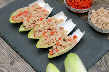 Endives dish filled with tuna, red pepper and onion  - obrazy, fototapety, plakaty