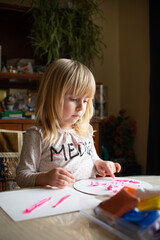 The little girl who sculpts with pink plasticine at home at the table by the window. Child development, home schooling, childhood. High quality photo