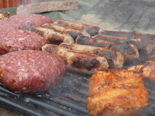 burgers, sausages, and chicken breast cooking on a barbecue grill