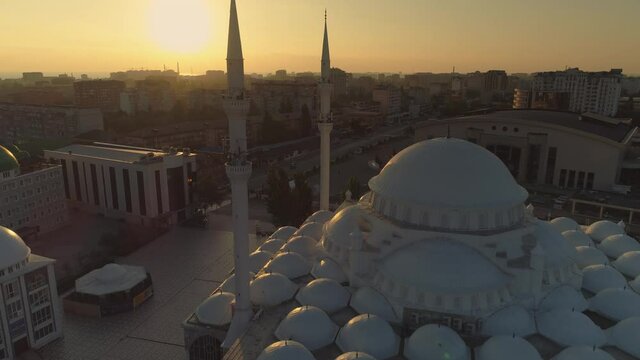 Aerial forward motion  central Juma minarets mosque at picturesque orange dawn, sun rays passes through towers. Makhachkala Dagestan Muslim landmark. Prayer times. Beautiful cityscape downtown film