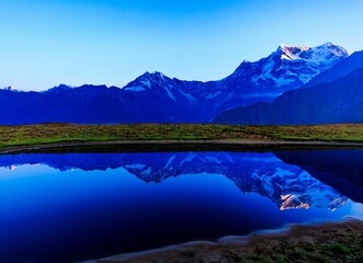 reflection of snow capped mountain on the lake in blue hour