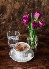 Coconut candy, cappuccino and a bouquet of tulips on a wooden background