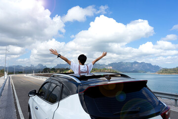 Travel, summer holidays. Rear view of young happy people enjoying road trip in their convertible and raising their arms up