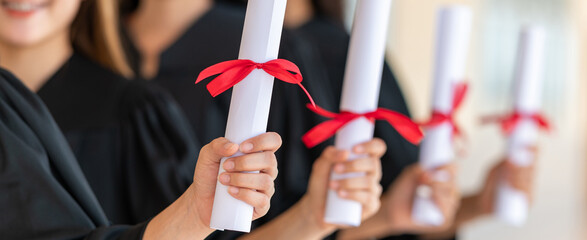 group of graduates Asian student in academic gown and graduation cap holding diploma